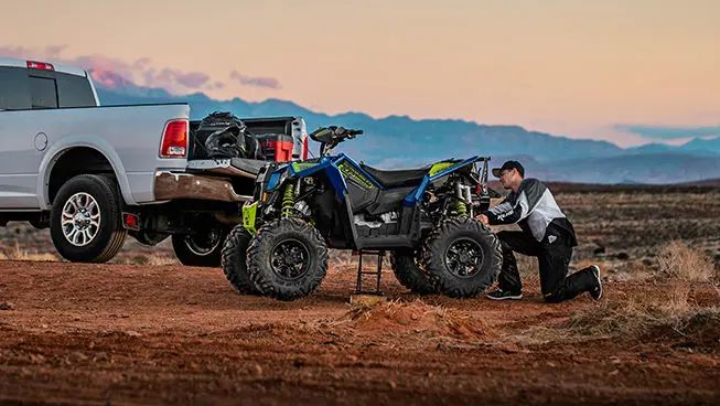 man adjusting the rear-end of his Scrambler XP 1000 S atv
