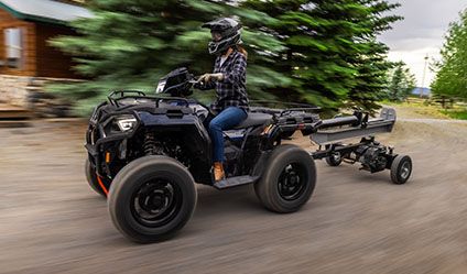 Mujer conduciendo un Sportsman 570 que jala un remolque