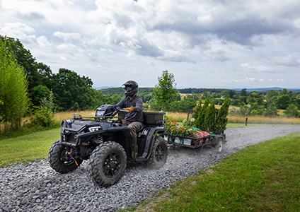 man pulling a trailer with polaris sportsman 850 with equipped accessories from the worker collection