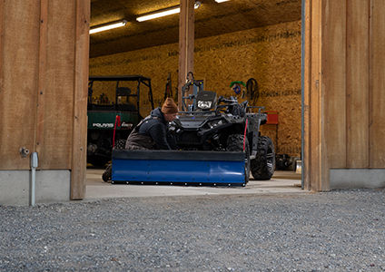 homme attachant un chasse-neige à son polaris sportsman 850 avec des accessoires de la collection hivernale