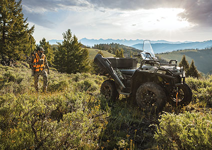 homme marchant vers son polaris sportsman 850 avec des accessoires de la collection pour chasseur