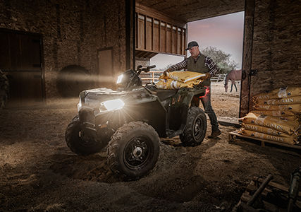 man loading feed onto rear rack of his polaris sportsman 850