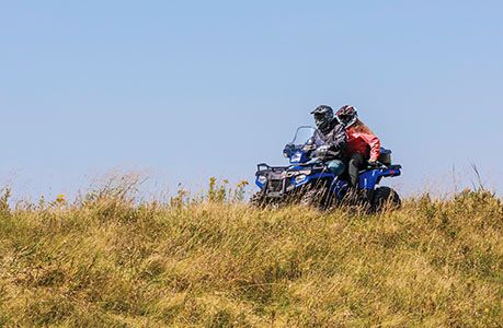 2 riders on a polaris sportsman touring 570  cruising through a field