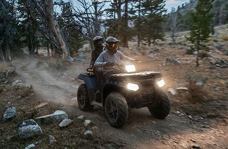 2 riders on a polaris sportsman touring 850 with lights on driving at dusk