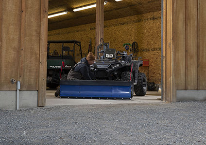 homme attachant un chasse-neige à son polaris sportsman xp 1000 avec des accessoires de la collection hivernale