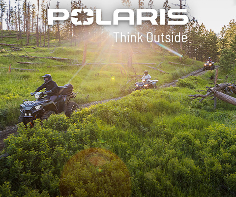 Polaris Sportsman ATVs riding across an open field