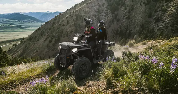 couple à bord d’un vtt sportsman touring dans une prairie