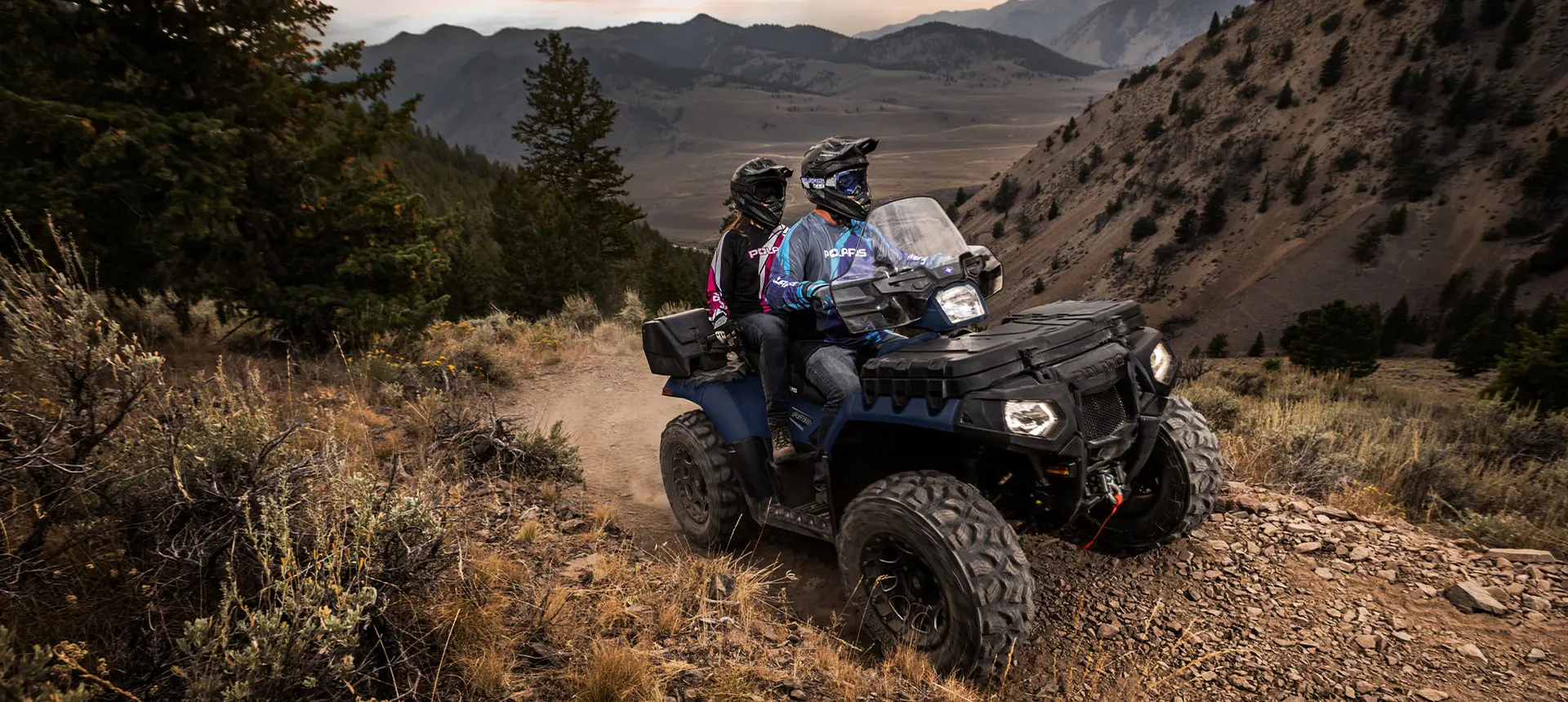 couple à bord d’un vtt polaris Sportsman Touring descendant une colline rocheuse
