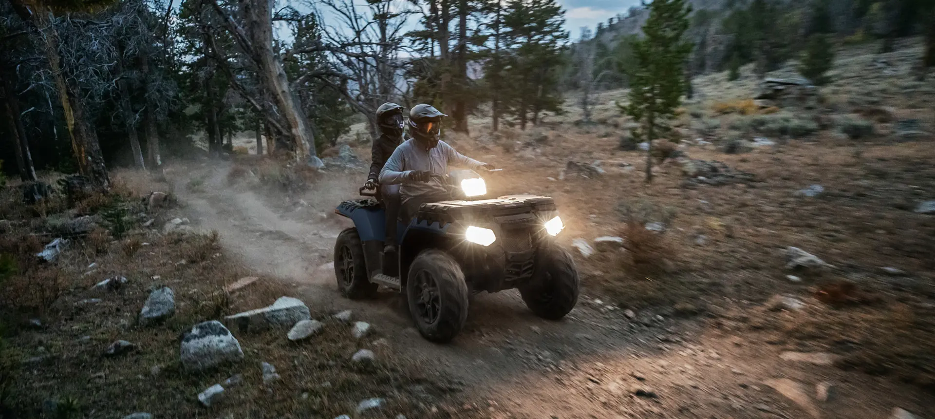 couple circulant au crépuscule dans un vtt Sportsman Touring avec phares allumés