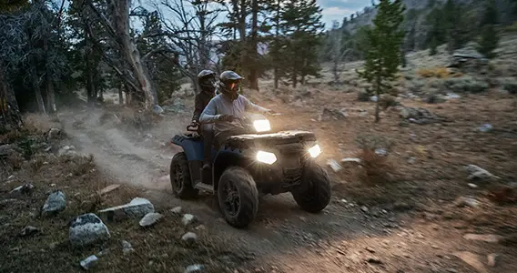 couple circulant au crépuscule dans un vtt Sportsman Touring avec phares allumés