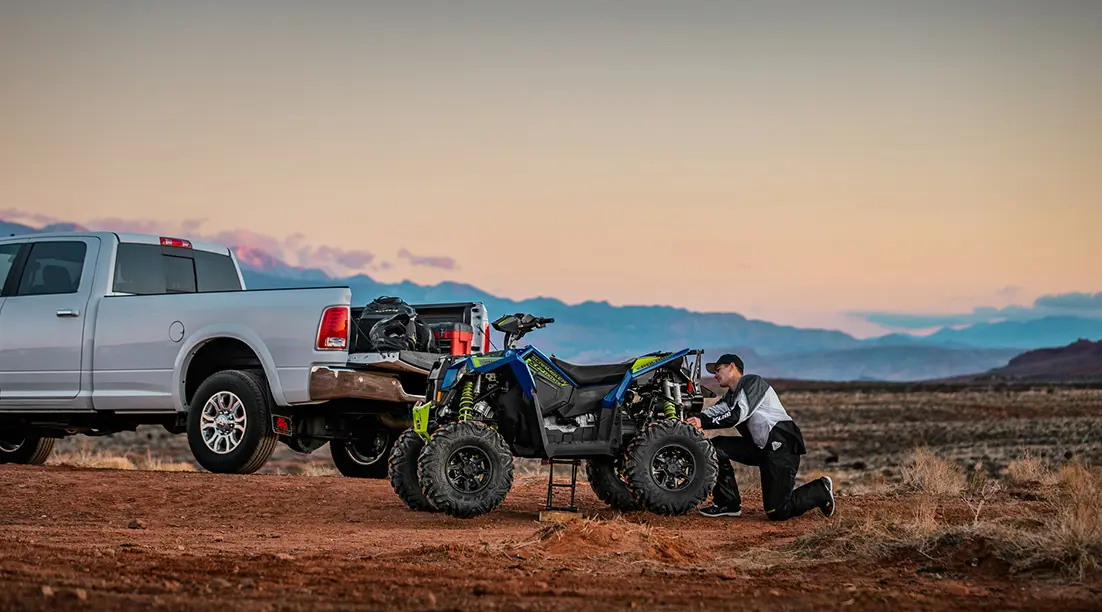 man adjusting the rear end on his polaris scrambler xp 1000 s atv