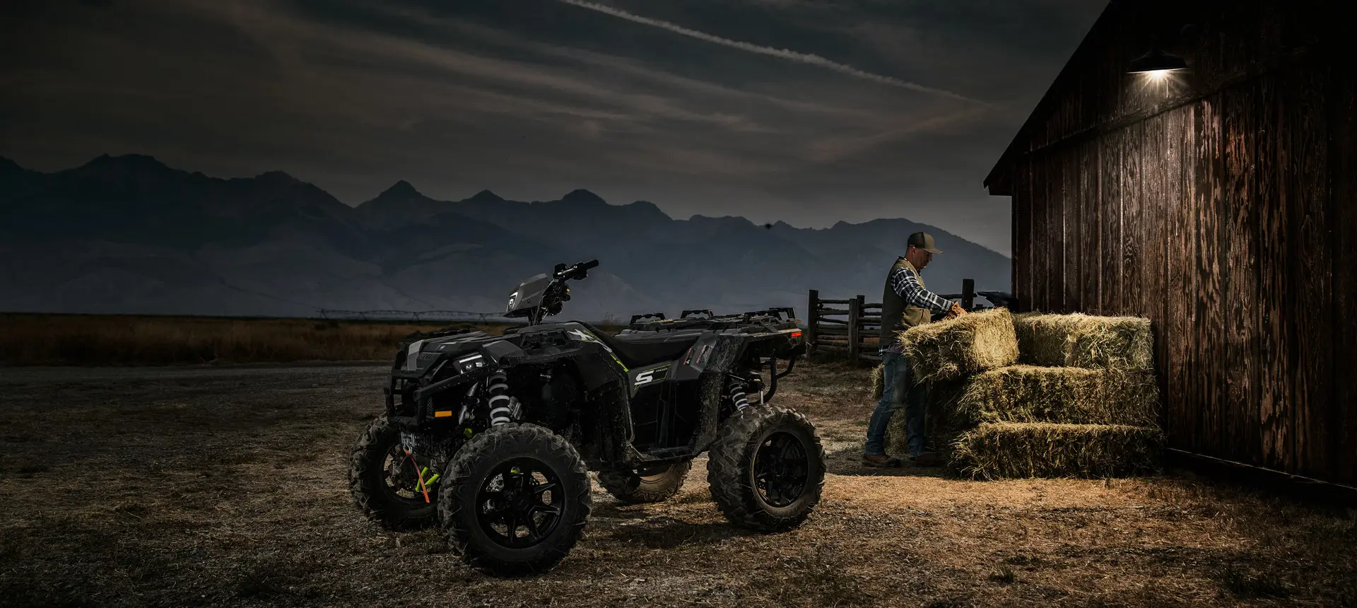man working with square bales near a sportsman xp 1000 s atv