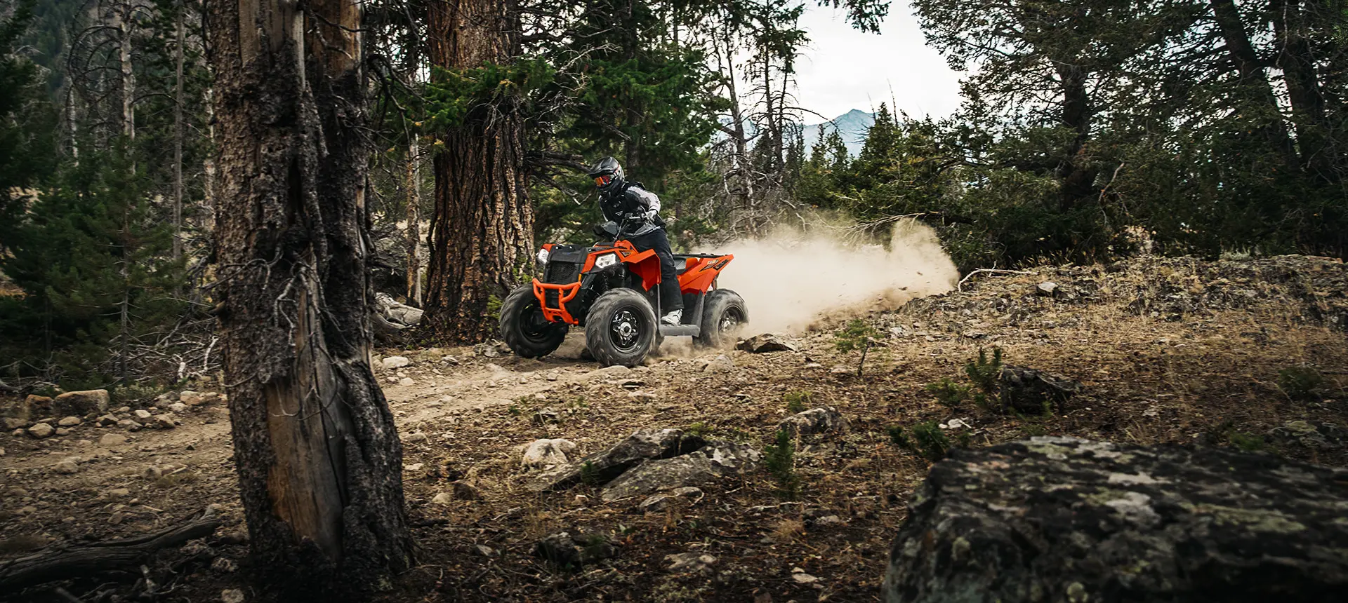 orange burst scrambler atv on a forest trail