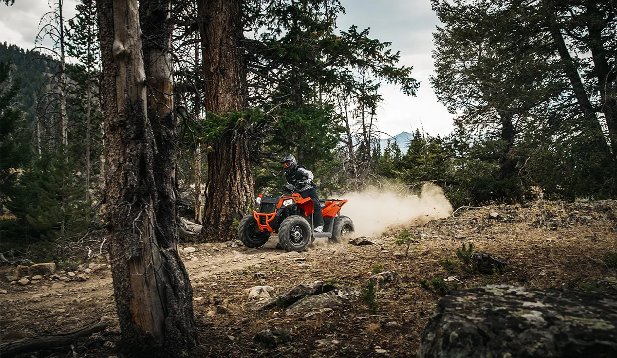 orange burst scrambler atv on a forest trail