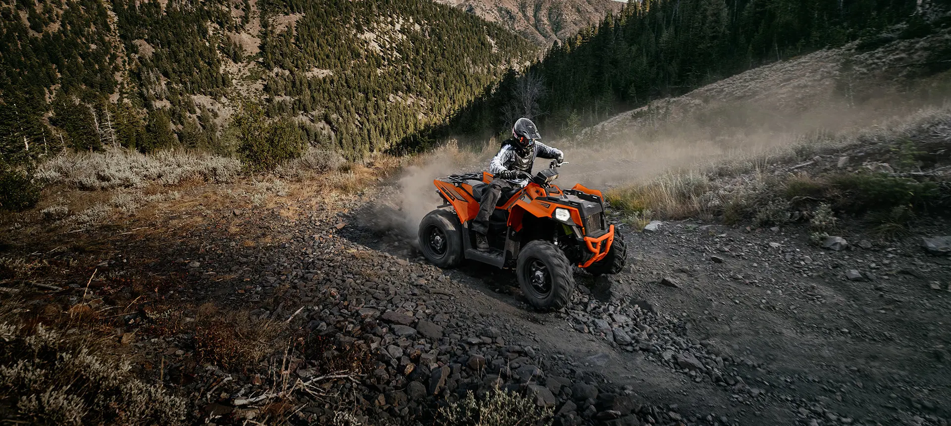 side profile of an orange burst scrambler atv on a hillside