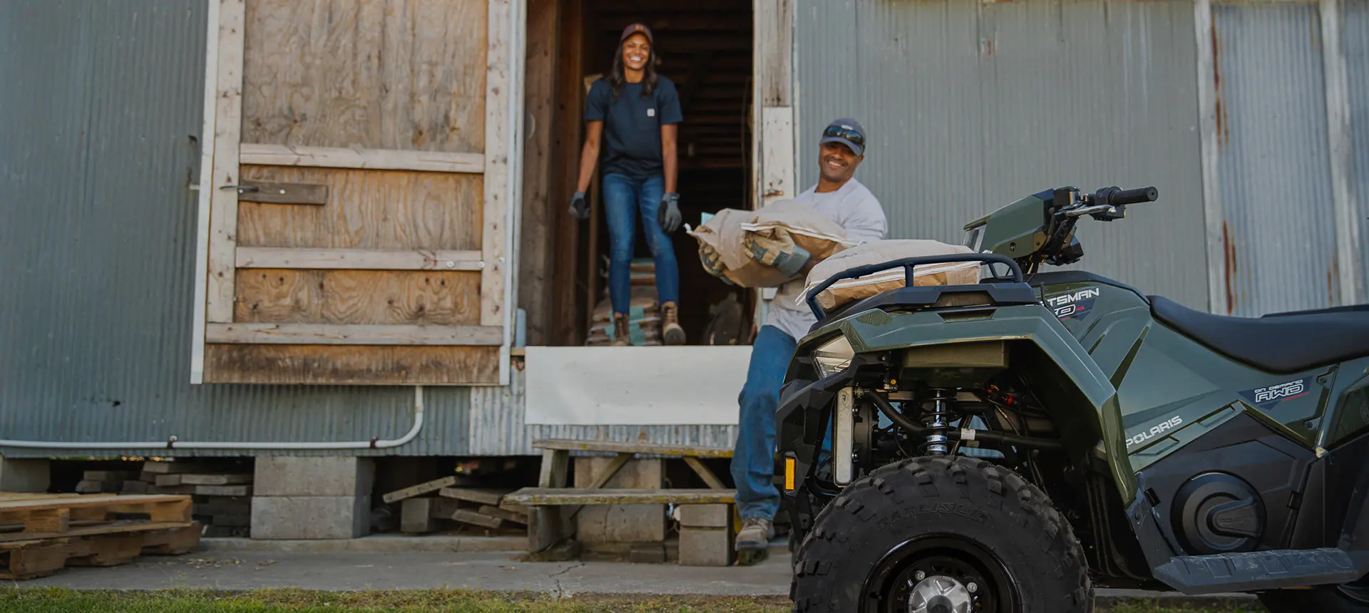 man hauling feedbags and loading them on the front of his sportsman 450 atv