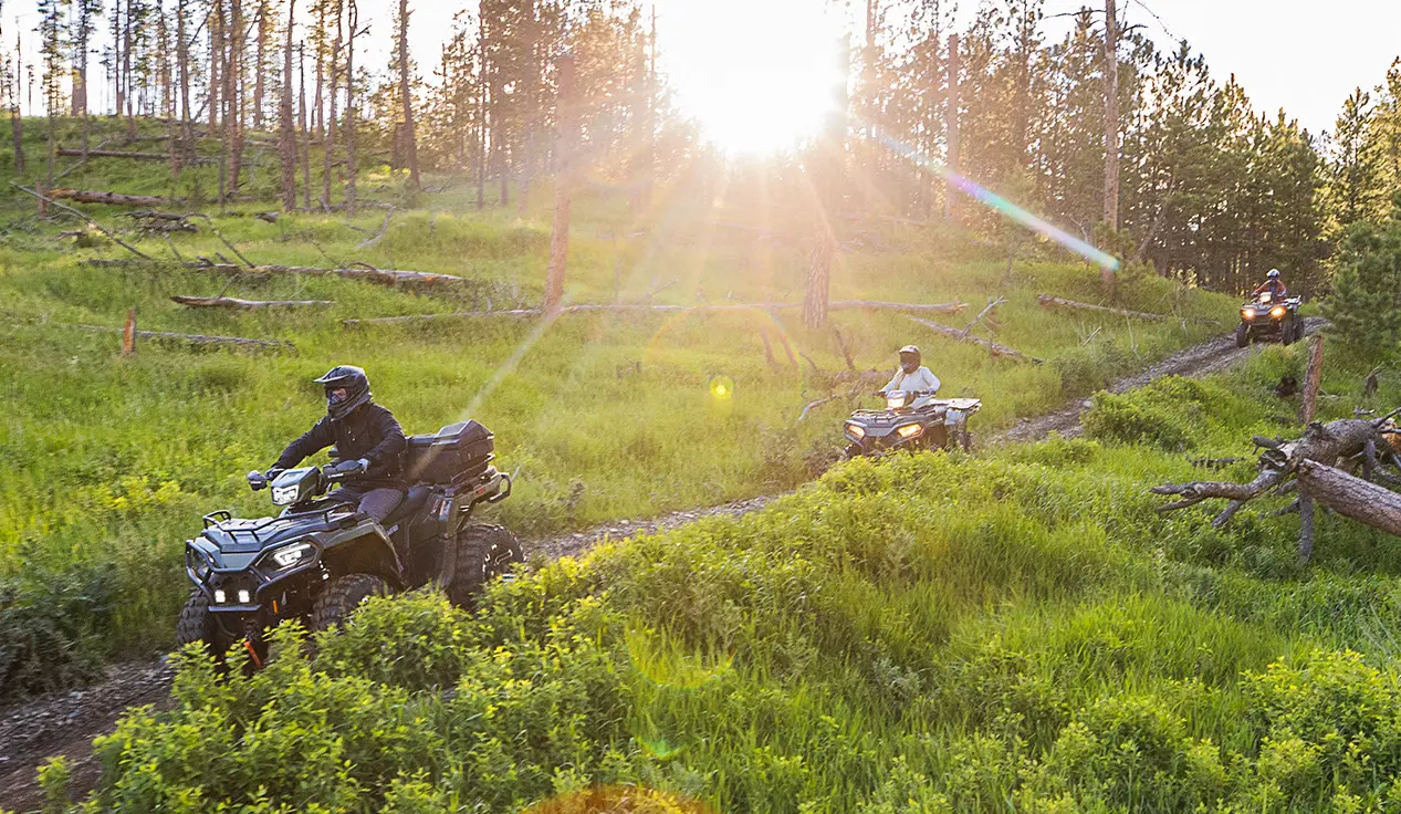 3 polaris sportsman 570 atvs cruising on a trail