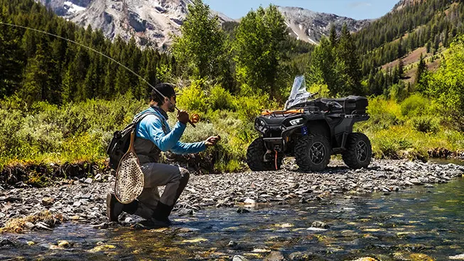 2 people relaxing after a ride on their polaris sportsman 570 atvs