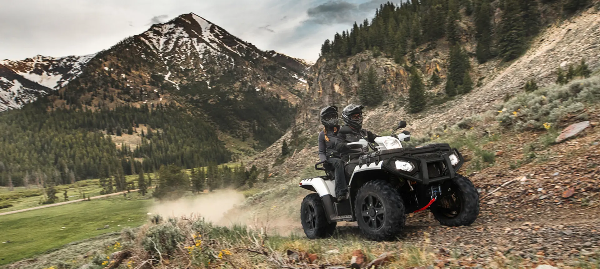 2 riders on a polaris sportsman touring xp 1000 cruising down a trail