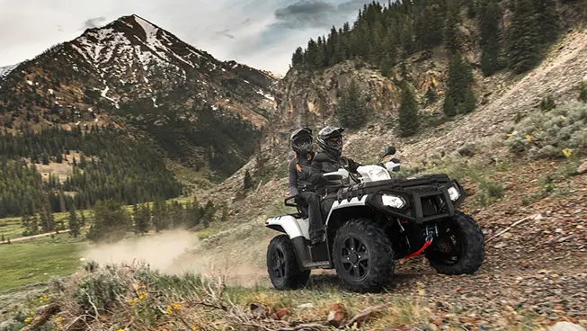 2 riders on a polaris sportsman touring xp 1000 cruising down a trail