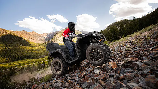 conductor en un atv sportsman xp 1000 ascendiendo una colina rocosa