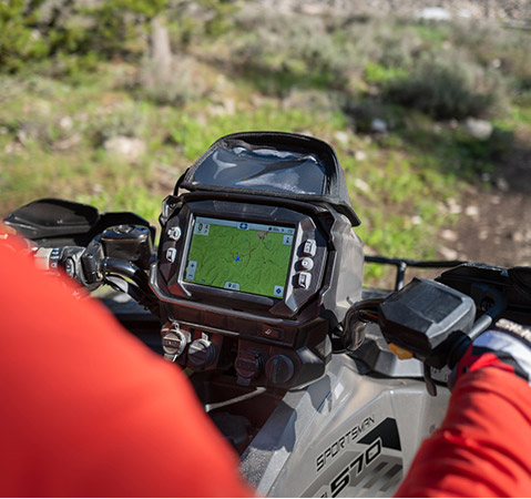A rider's view from a Polaris Sportsman ATV, showing the handlebars and the Polaris RIDE COMMAND display with a trail map.
