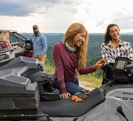 Woman using the 7-inch RIDE COMMAND touch screen on her 2025 Polaris Sportsman 570 ATV.