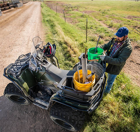 Man using fence-fixing equipment he carried to a worksite with the rack extender on a 2025 Polaris Sportsman 450 ATV.