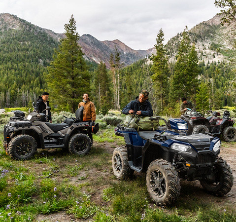 Three Polaris Sportsman 850 ATVs loaded with camping gear for an overnight adventure.