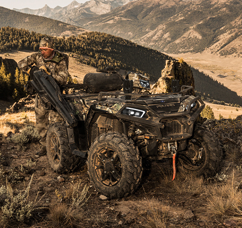 A hunter grabbing his rifle from the gun boot accessory attached to his 2025 Polaris Sportsman Hunt Edition ATV.