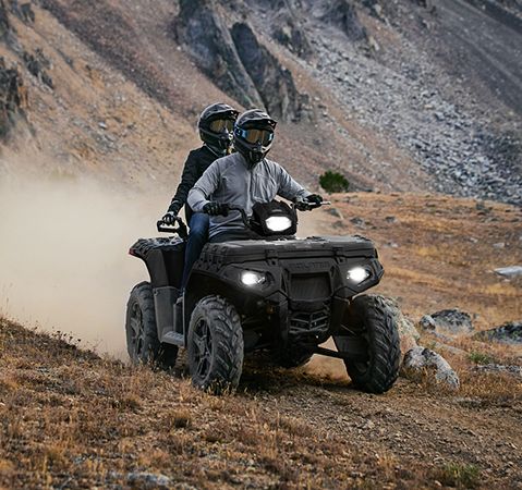 2 passengers on a 2025 Polaris Sportsman Touring 850 ATV, cruising down a narrow trail and showcasing its nimble 48-inch width.