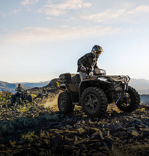 A rider cruising smoothly over rocky terrain on a 2026 Polaris Sportsman ATV.