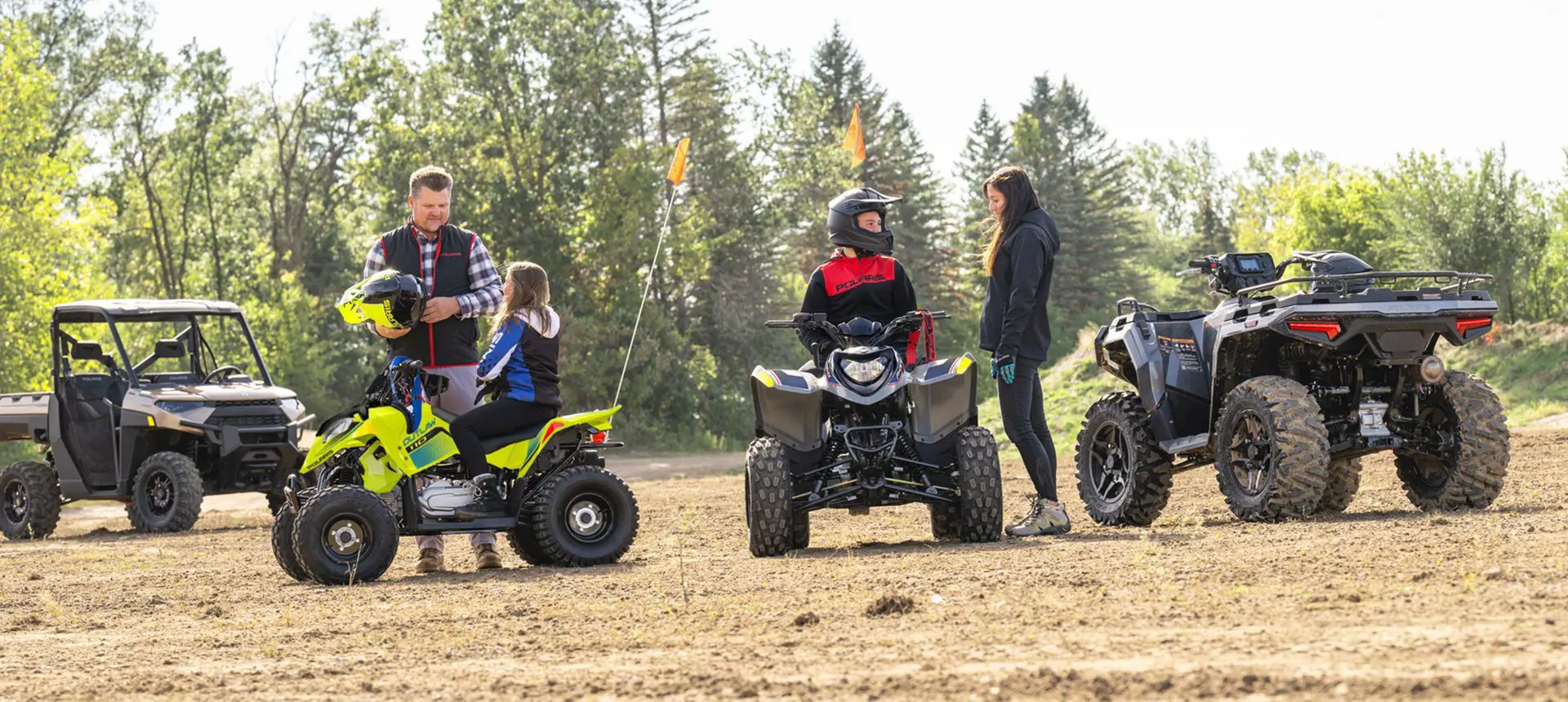 Parents talking to their kids before they ride their 2026 Polaris Outlaw 110 EFI youth ATVs.