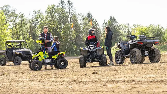 Parents talking to their kids before they ride their 2026 Polaris Outlaw 110 EFI youth ATVs.