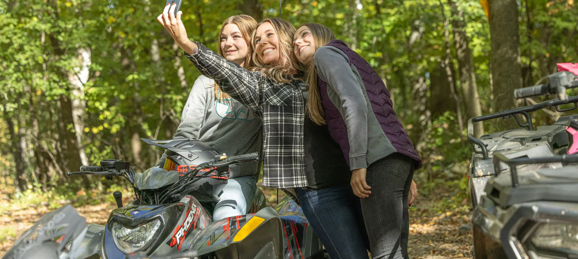 3 girls taking a selfie after a ride on their ATVs, including the 2026 Polaris Phoenix 200 youth ATV.