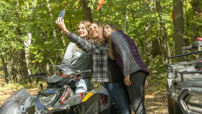 3 girls taking a selfie after a ride on their ATVs, including the 2026 Polaris Phoenix 200 youth ATV.