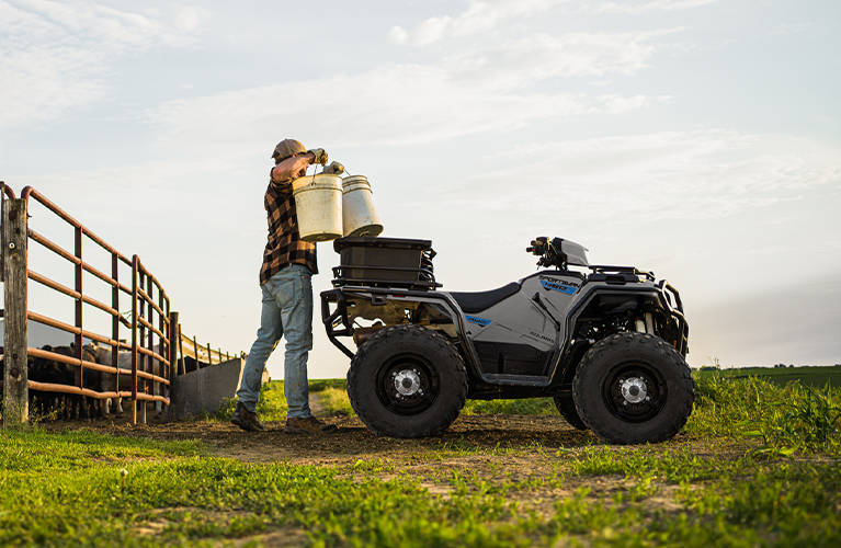 A rancher showcasing the 5 gallons of storage on the cargo rack of a 2026 Polaris Sportsman 450 ATV. 