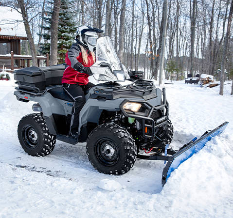 Femme en train de déneiger avec son VTT Polaris Sportsman 450 2026.