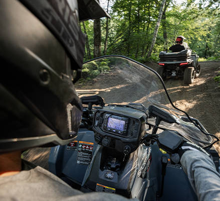 Over the shoulder view of a helmeted rider cruising a trail on a 2026 Polaris Sportsman 570 ATV.