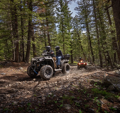 Deux personnes sur un VTT biplace Polaris Sportsman Touring 570 2026 présentant le nouveau pare-chocs avant et le treuil de 1 588 kg (3 500 lb).