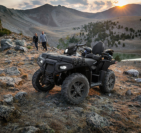 2 people walking towards a parked 2026 Polaris Sportsman Touring 850 Premium ATV showcasing the 6 gallons of integrated storage.