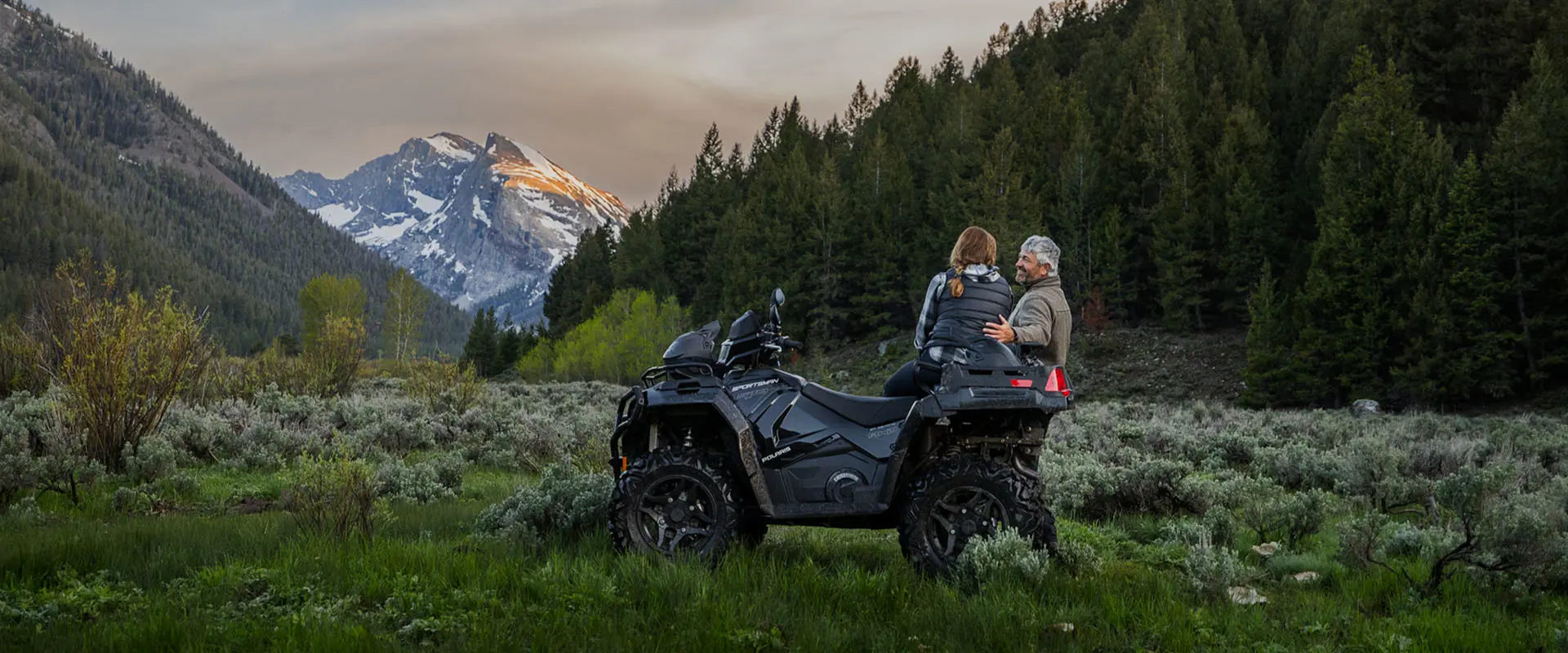 A couple enjoying the scenery from the comfort of a 2026 Polaris Sportsman X2 570 ATV.