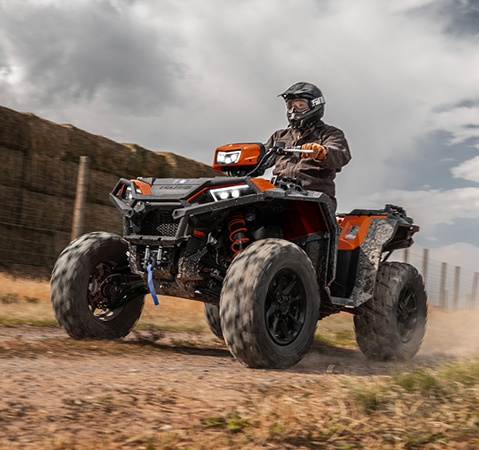 A helmeted rider cruising on the 55-inch wide 2026 Polaris Sportsman XP 1000 S ATV. 