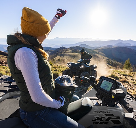 Woman sitting on a 2026 Sportsman XP 1000 ATV looking down at the 7-inch RIDE COMMAND touch screen display. 