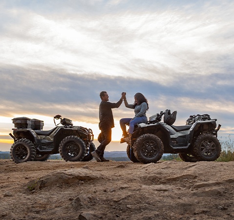 2 people clasping hands after a ride on their 2026 Sportsman XP 1000 ATVs.