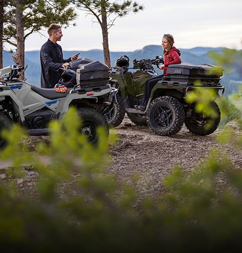 2 people taking a break after a ride on their versatile 2027 Polaris Sportsman ATVs.
