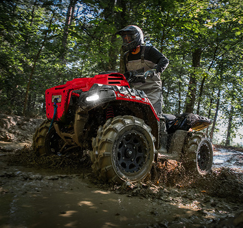 A rider on a 2027 Polaris Sportsman Mud Edition ATV showcasing the sealed LED headlights.