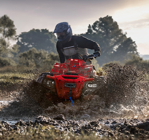 A rider on a 2027 Polaris Sportsman Mud Edition ATV powering through a deep mud pit. 