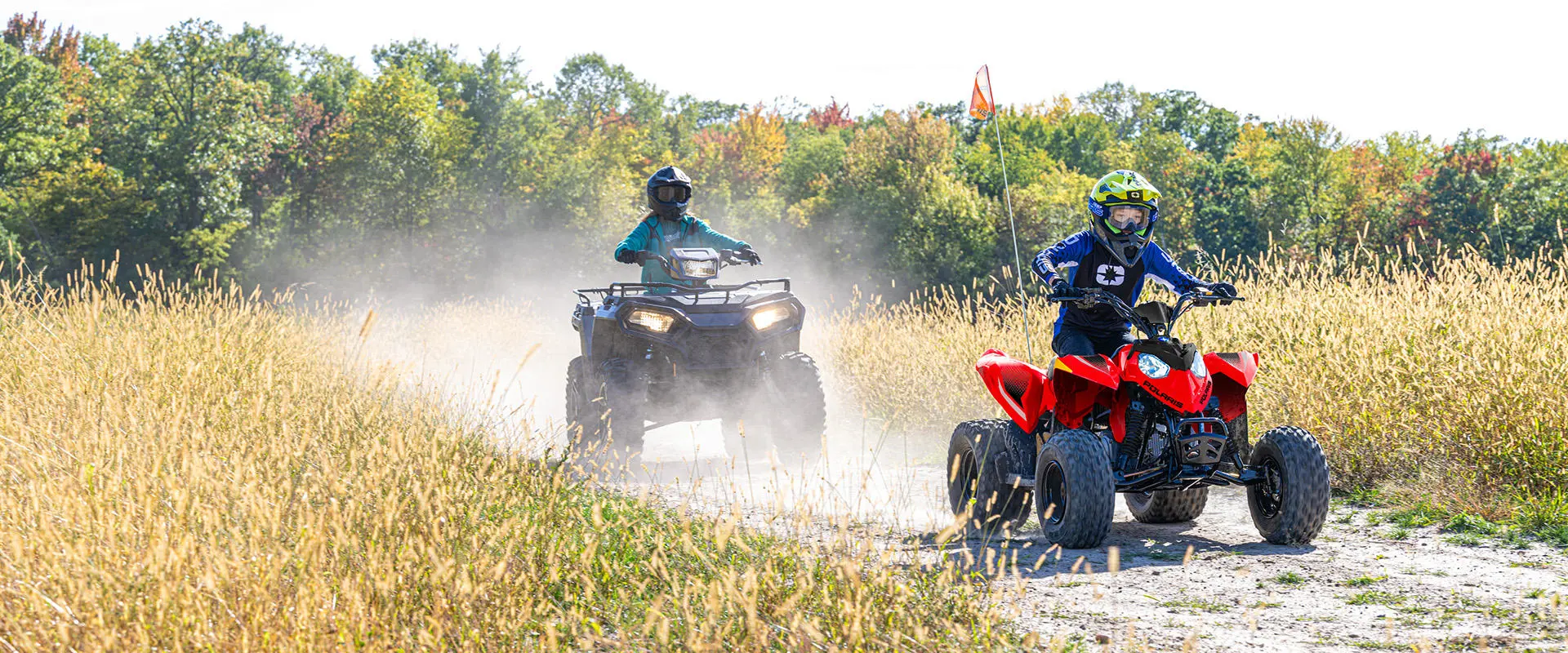A kid trail riding on an Indy Red 2027 Polaris Outlaw 110 EFI youth ATV.