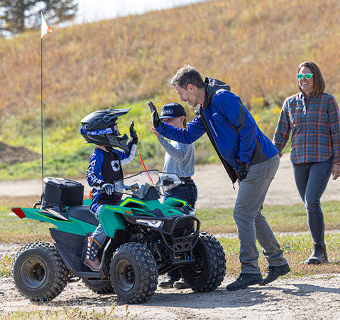 A kid smiling while sitting on a 2026 Polaris Outlaw 70 EFI youth ATV.